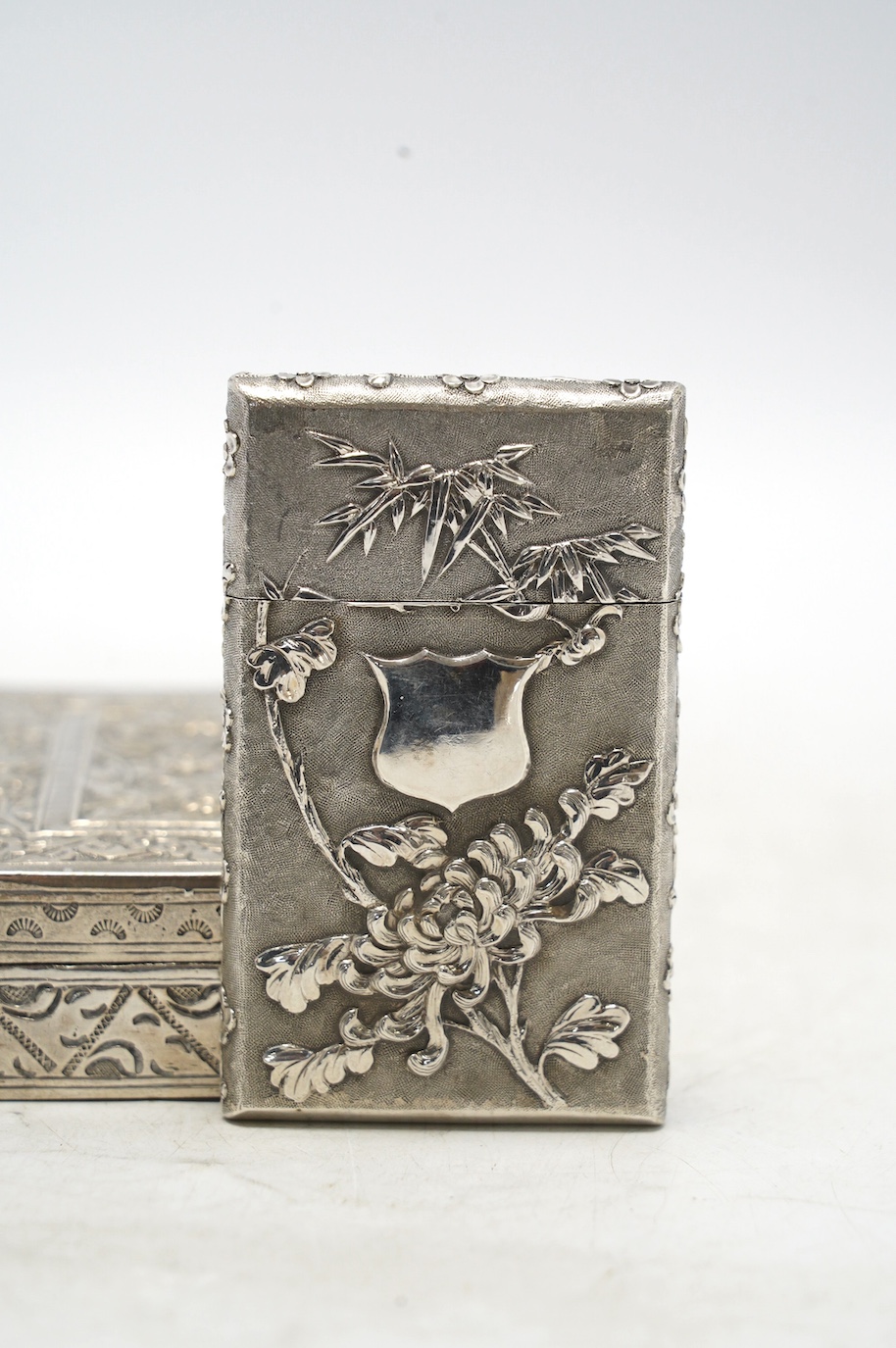 An early 20th century Chinese Export white metal card case by Wang Hing, 84mm, together with a Chinese white metal box with hinged cover. Condition - fair to good